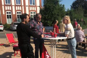 Drei Personen an einem Standtisch im Gespräch. Bahnhofsvorplatz Sörup