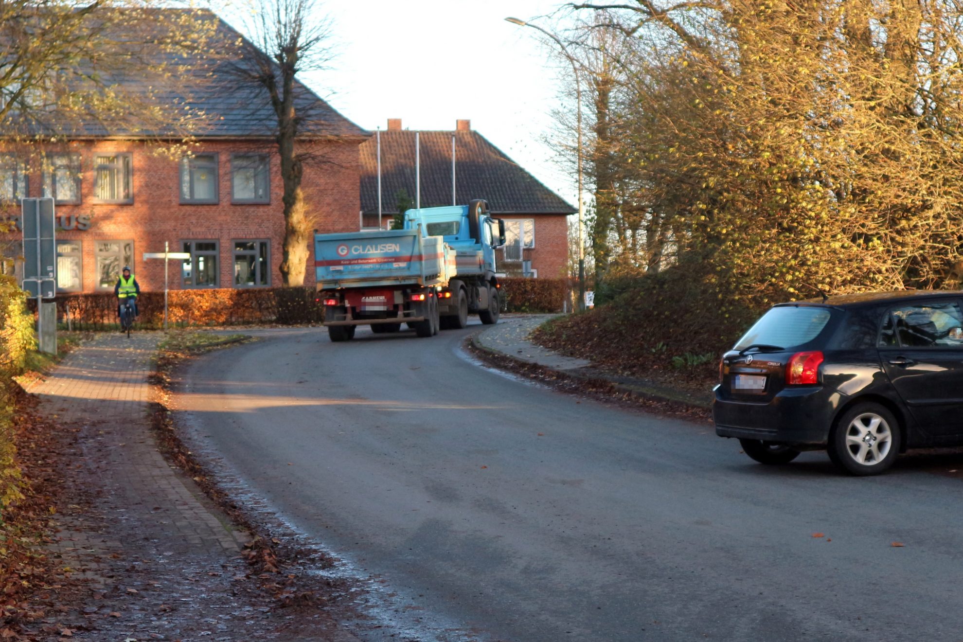 Schulstraße in Sörup, ein LKW befährt die Straße und ein PKW fährt in die Straße