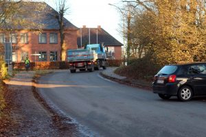 Schulstraße in Sörup, ein LKW befährt die Straße und ein PKW fährt in die Straße