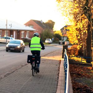 Schulstraße, Sörup Richtung Ortsausgang. PKW und Radfahrer